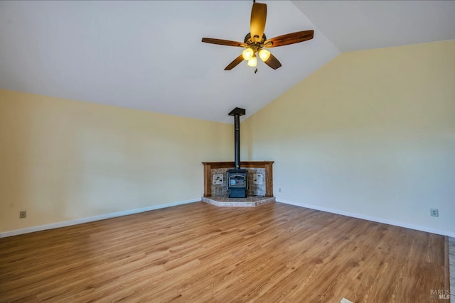 unfurnished living room with lofted ceiling, light hardwood / wood-style floors, ceiling fan, and a wood stove