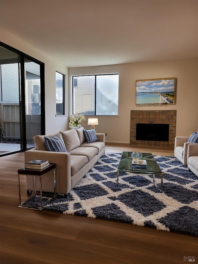 living room featuring a tiled fireplace and wood-type flooring