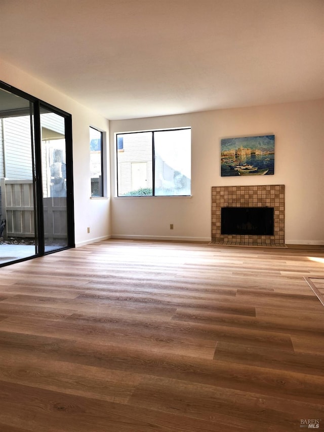 unfurnished living room with a tile fireplace and wood-type flooring