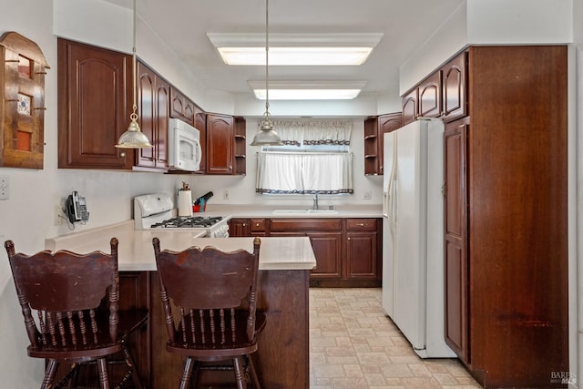 kitchen featuring kitchen peninsula, white appliances, a kitchen bar, and hanging light fixtures