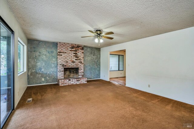 unfurnished living room featuring a textured ceiling, ceiling fan, dark carpet, and a fireplace