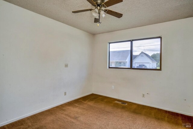 carpeted empty room featuring ceiling fan and a textured ceiling