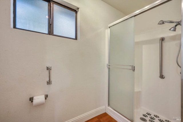 bathroom with a wealth of natural light, a shower with shower door, and hardwood / wood-style flooring