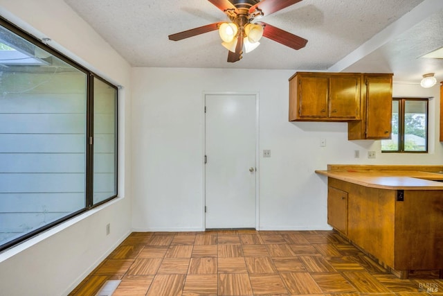 kitchen with dark parquet flooring, ceiling fan, and a textured ceiling