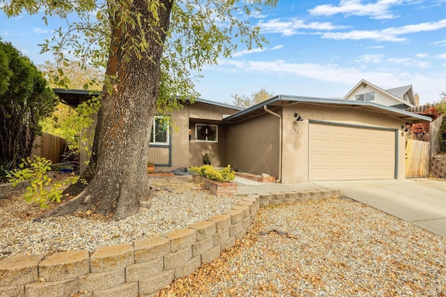 single story home featuring driveway, stucco siding, fence, and an attached garage