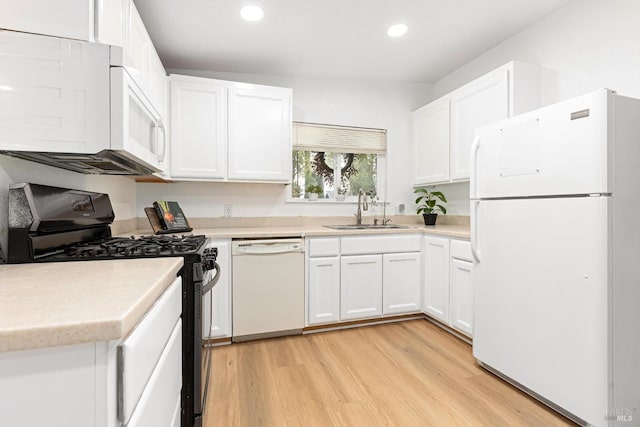 kitchen featuring white appliances, light wood-style flooring, white cabinetry, recessed lighting, and a sink