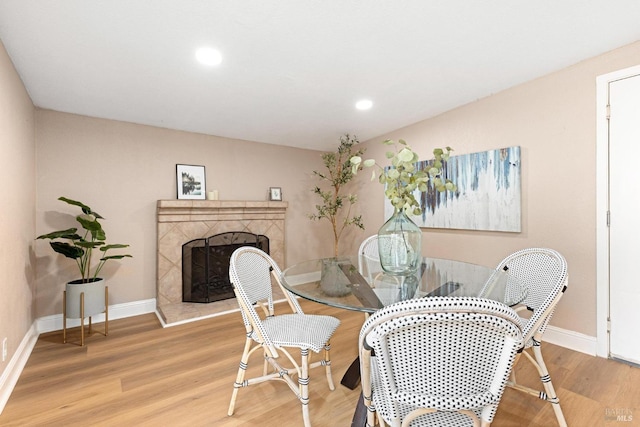 dining space featuring wood-type flooring and a tile fireplace