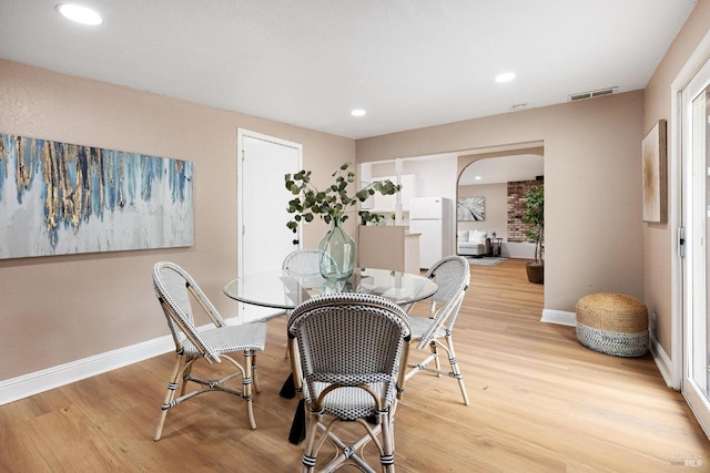 dining room with light wood finished floors, visible vents, and baseboards