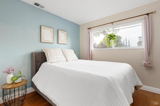 bedroom with visible vents, baseboards, and wood finished floors