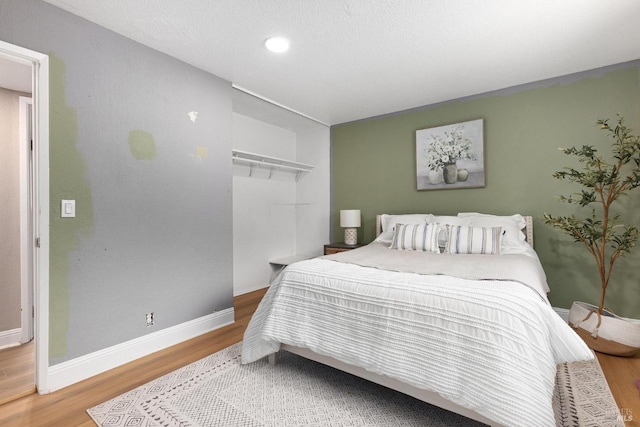 bedroom with wood finished floors, baseboards, and recessed lighting
