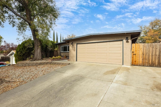 ranch-style home with concrete driveway, stucco siding, fence, and a garage