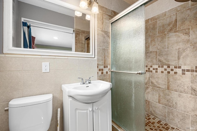 bathroom featuring vanity, toilet, an enclosed shower, and tile walls