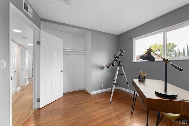 office space featuring visible vents, baseboards, wood finished floors, and a textured ceiling