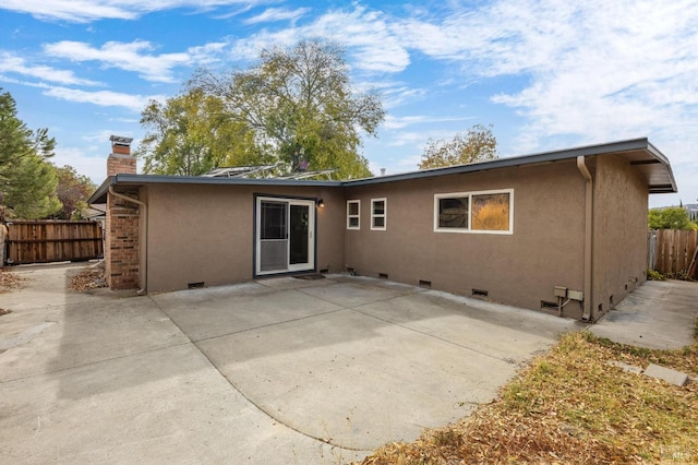 back of property with crawl space, a patio area, and fence