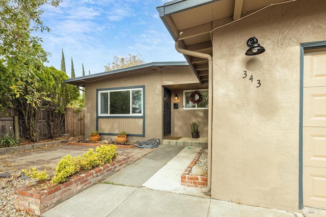 doorway to property featuring fence and stucco siding