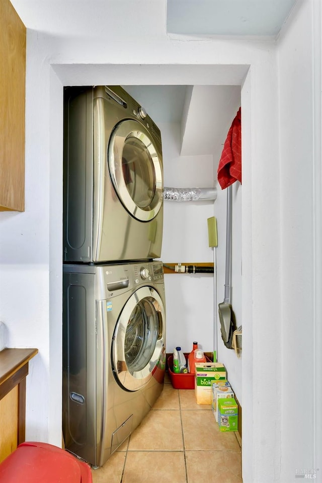 clothes washing area with light tile patterned floors and stacked washer / drying machine