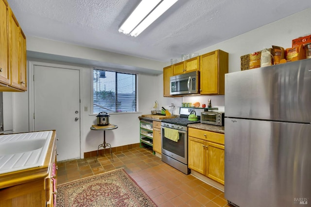 kitchen featuring appliances with stainless steel finishes, a textured ceiling, and sink