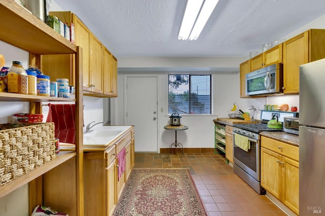 kitchen featuring a textured ceiling, sink, stainless steel appliances, and tile patterned floors