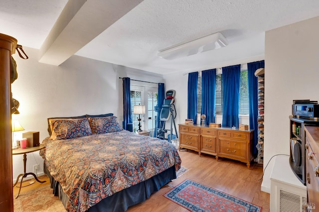 bedroom featuring light wood-type flooring and a textured ceiling