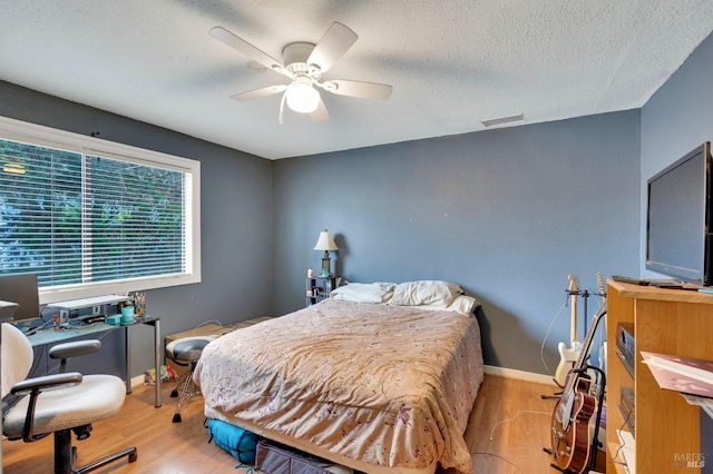 bedroom with a textured ceiling, light hardwood / wood-style flooring, and ceiling fan