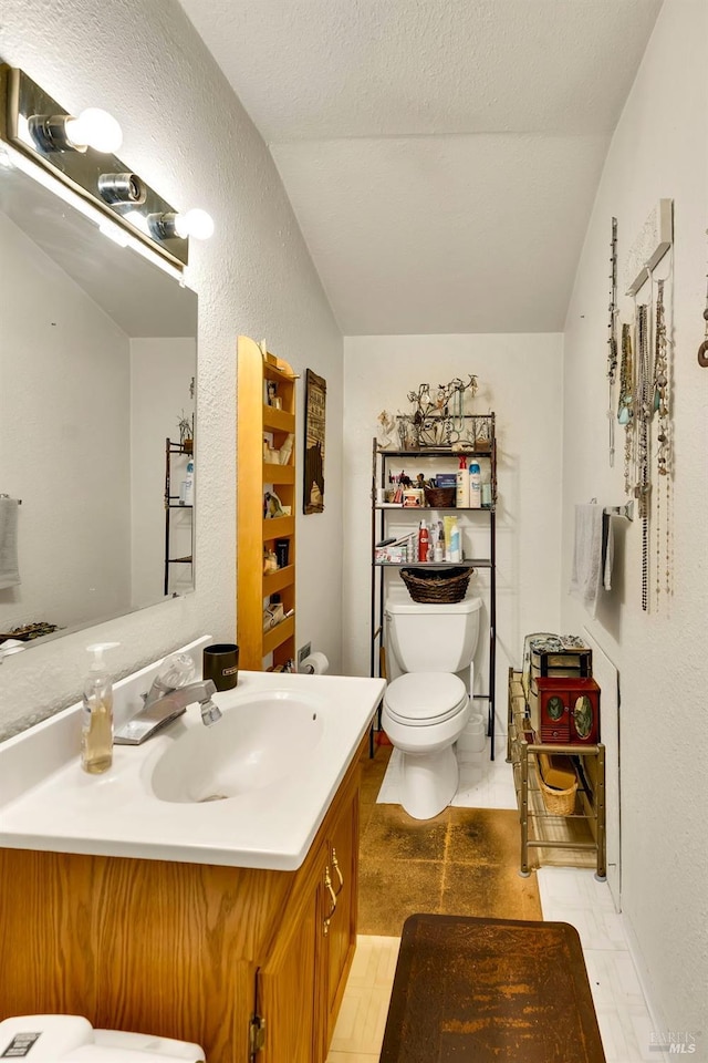 bathroom with tile patterned floors, a textured ceiling, vanity, vaulted ceiling, and toilet