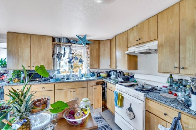 kitchen featuring light stone countertops, light tile patterned floors, a textured ceiling, and gas range gas stove