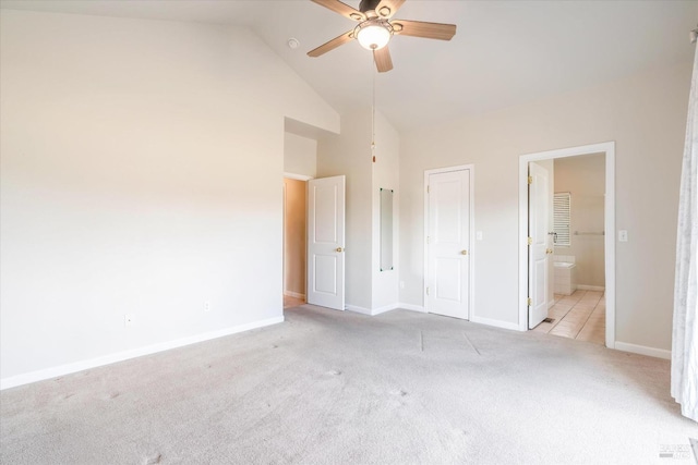 unfurnished bedroom featuring high vaulted ceiling, light colored carpet, ceiling fan, and ensuite bath