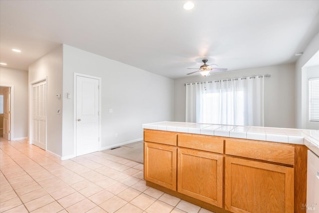 kitchen with tile counters, a healthy amount of sunlight, ceiling fan, and light tile patterned floors