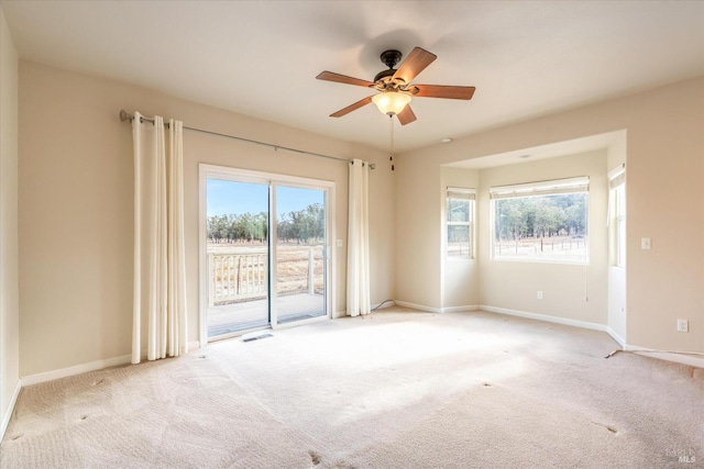 unfurnished room featuring ceiling fan, plenty of natural light, and light carpet