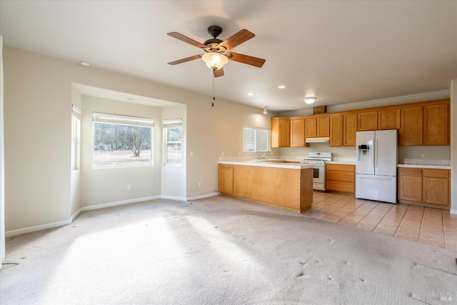 kitchen featuring kitchen peninsula, white appliances, light carpet, and ceiling fan