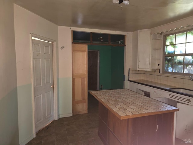 kitchen with sink, tile countertops, white cabinetry, and backsplash