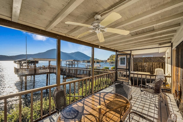 interior space with a water and mountain view and ceiling fan