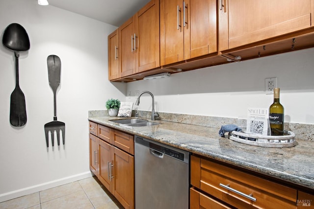 kitchen with light stone countertops, sink, light tile patterned floors, and stainless steel dishwasher