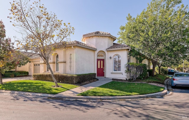 mediterranean / spanish house featuring a garage and a front yard