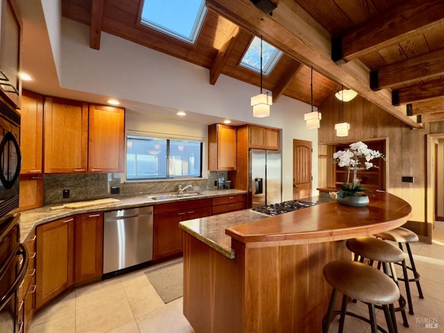 kitchen with appliances with stainless steel finishes, pendant lighting, sink, lofted ceiling with skylight, and a center island