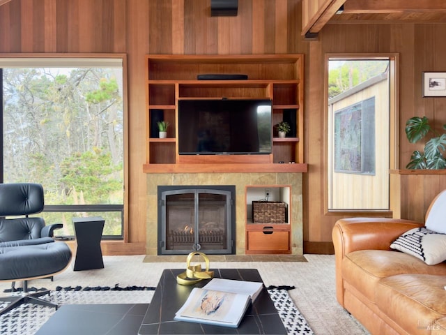 living room featuring a wealth of natural light, a tiled fireplace, and wooden walls