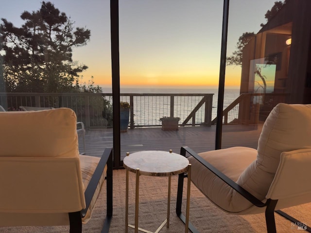 balcony at dusk featuring a deck with water view