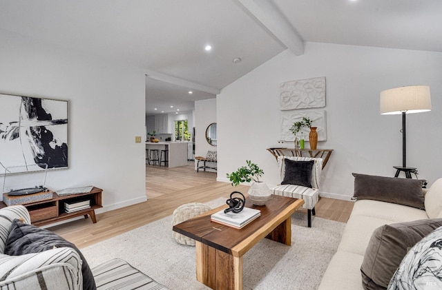 living room with light hardwood / wood-style floors and vaulted ceiling with beams