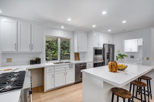 kitchen with a kitchen breakfast bar, sink, appliances with stainless steel finishes, and white cabinets