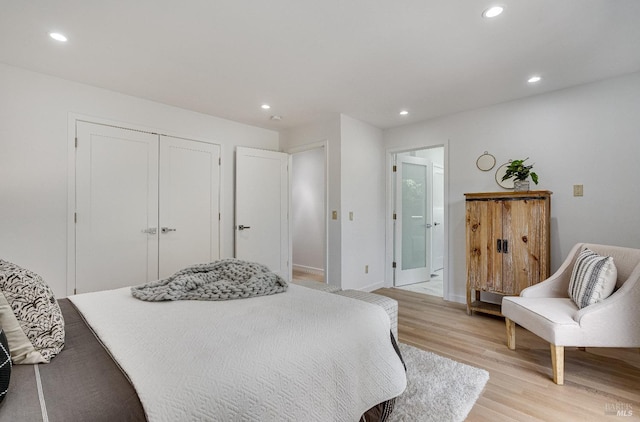 bedroom with light wood-type flooring, a closet, and ensuite bath