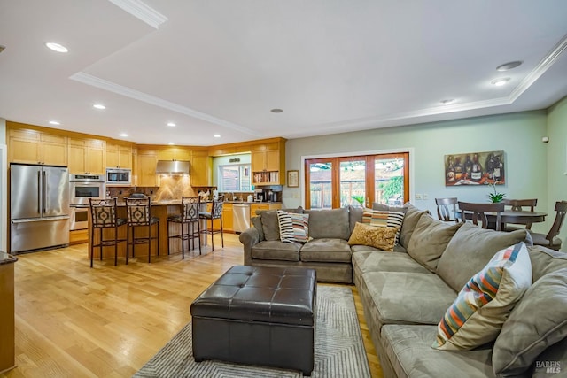 living room featuring a raised ceiling, crown molding, and light hardwood / wood-style floors