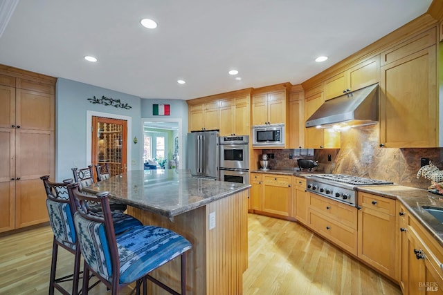 kitchen featuring a kitchen bar, stone counters, a center island, and stainless steel appliances