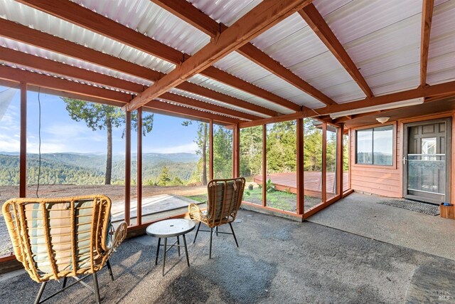 sunroom / solarium featuring beam ceiling and a mountain view