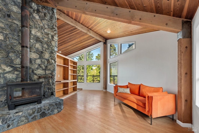 living room featuring beamed ceiling, light hardwood / wood-style floors, a wood stove, high vaulted ceiling, and wooden ceiling