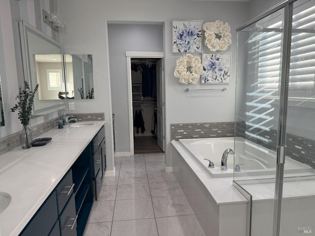 bathroom with a wealth of natural light, vanity, tiled tub, and tile patterned floors