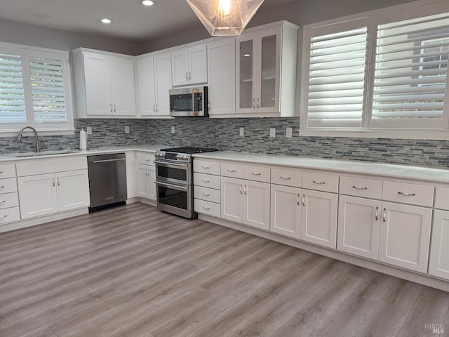 kitchen featuring white cabinetry, light wood-type flooring, appliances with stainless steel finishes, and sink