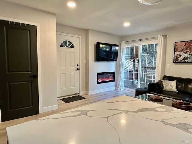 entryway with a glass covered fireplace, recessed lighting, wood finished floors, and baseboards