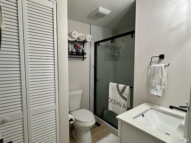 bathroom with visible vents, toilet, a marble finish shower, a closet, and vanity