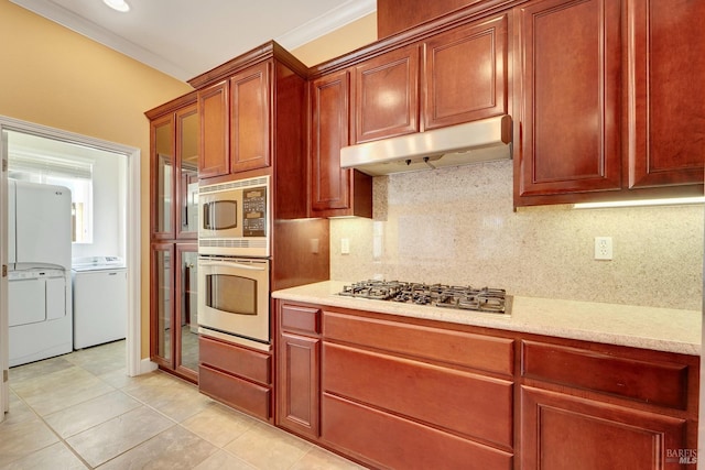 kitchen featuring appliances with stainless steel finishes, crown molding, under cabinet range hood, separate washer and dryer, and backsplash