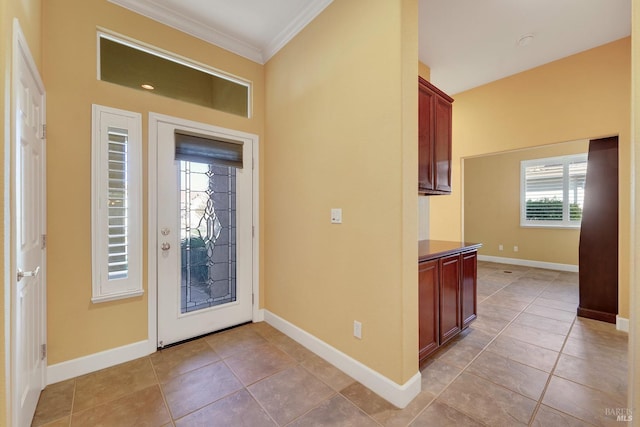 entryway with light tile patterned floors, baseboards, and crown molding